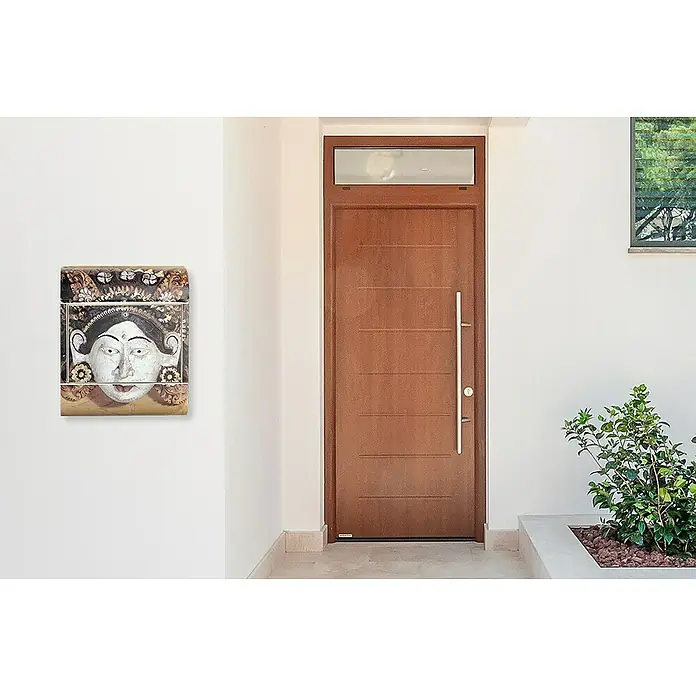 Wandbriefkasten - L x B x H: 12 x 38 x 45 cm, Stahl, Zeitungsfach, Bali - Das Foto zeigt eine moderne Haustür aus Holz mit einem Briefkasten mit einem stilisierten Frauengesicht an einer weißen Wand.