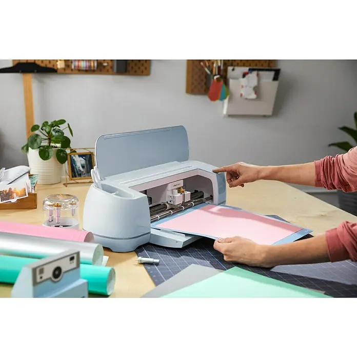Cricut Prensa de transferencia Mug Press - Específico para: Tazas compatibles con Infusible Ink - Máquina de corte Cricut en uso. El usuario está introduciendo un tapete rosa para preparar el corte con la Cricut Explore 3.