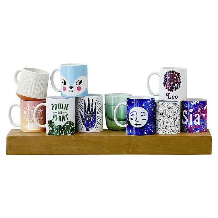 Cricut Transferpresse Mug Press - Passend für: Infusible Ink- und sublimationskompatible Tassenrohlinge - Vielfalt an Keramiktassen auf einem Regal: Jede Tasse zeigt ein einzigartiges Design, von Pflanzen bis zu Sternzeichen, perfekt für jeden Geschmack.