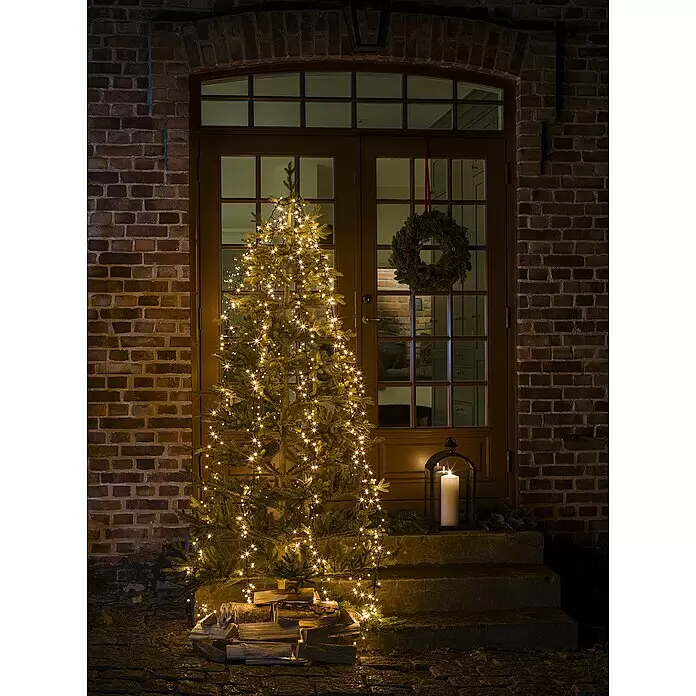 Konstsmide Baummantel - Außen, 2,4 m, 6 Stränge à 110 gefrostete bernsteinfarbene LEDs, Anzahl Leuchtmittel: 660 Stk., Lichtfarbe: Bernstein - Weihnachtsbaum mit warmweißen Lichterketten vor einer Haustür.