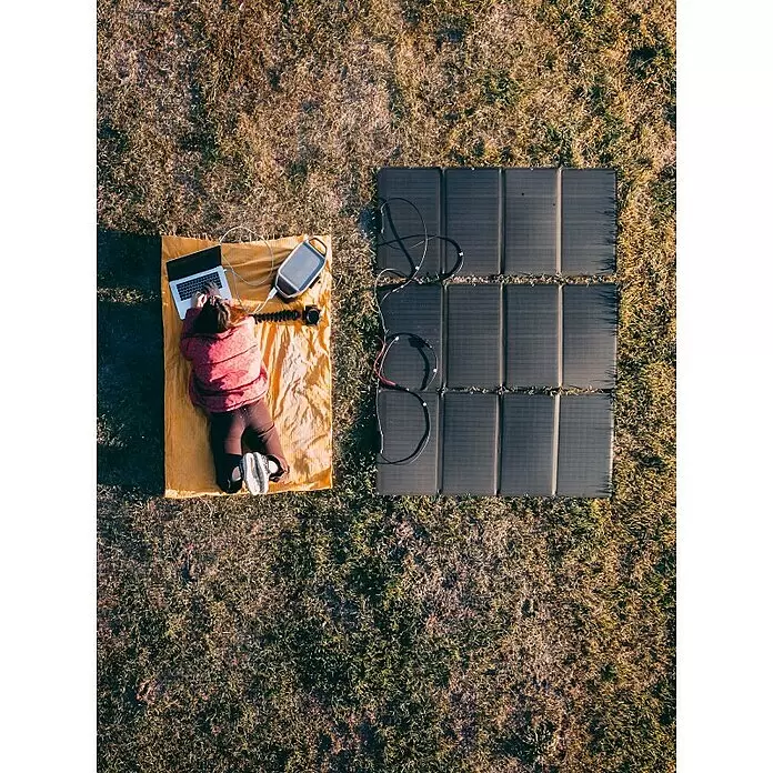 EcoFlow Solar-Verlängerungskabel - Schwarz, 3 m, 1 Stk. - Person nutzt Laptop, an graue Powerstation angeschlossen, draußen über schwarze faltbare Solarmodule geladen.