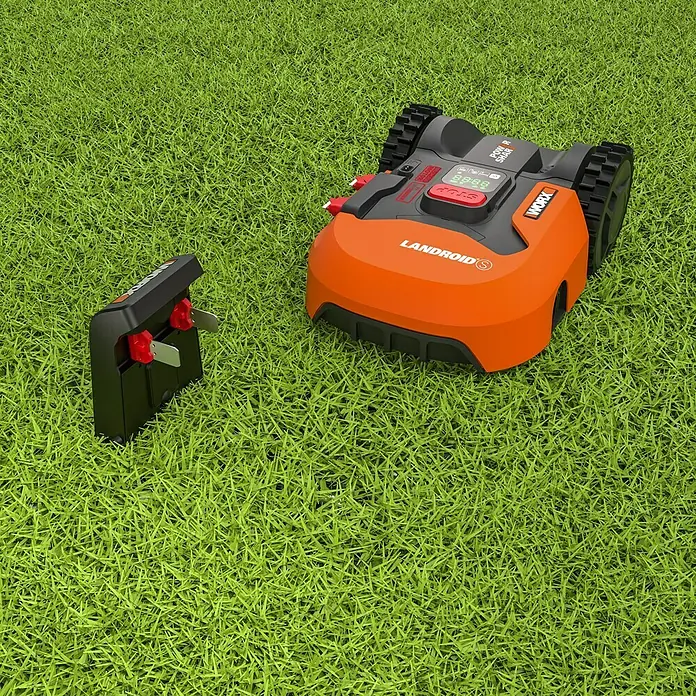 Worx PowerShare 20V Robot cortacésped Landroid M500 - 500 m², Ancho de corte: 18 cm, Navegación por inducción, Cable de antena - Robot cortacésped Worx Landroid S con estación de carga sobre césped verde. El robot es naranja y negro y tiene una pantalla.