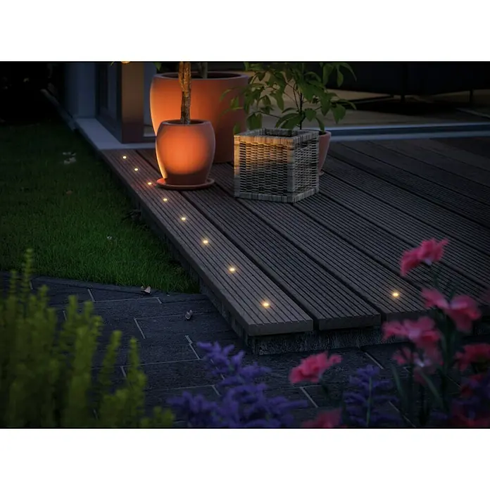 Paulmann Plug & Shine Set básico Micro Pen II - 0,22 W, Número de bombillas: 5 ud., Plata, 5 ud. - Terraza de madera con luces LED empotradas que crean un ambiente cálido, rodeada de plantas y flores.