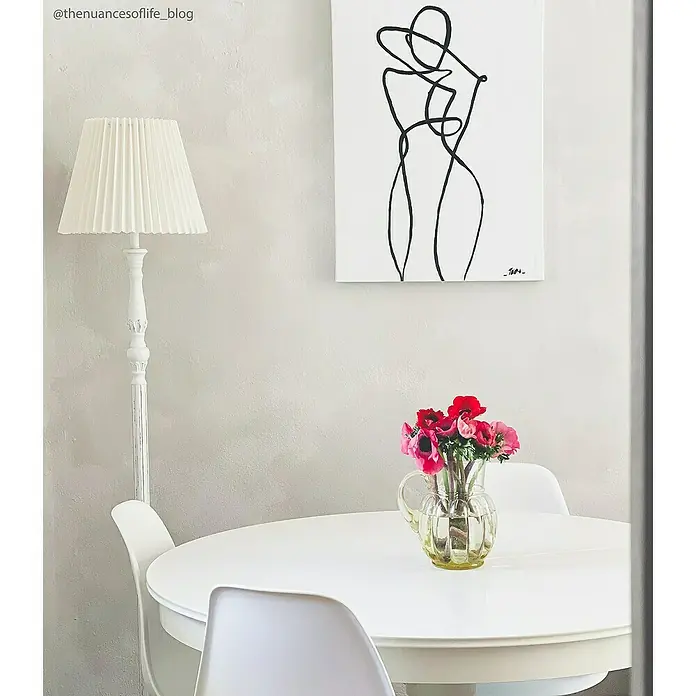 Fleur Pintura para efectos decorativos Lime Paint - Grey White, 750 ml, Mate - La imagen presenta una mesa con flores en un jarrón, una lámpara y una obra de arte en la pared, mostrando un interior elegante.