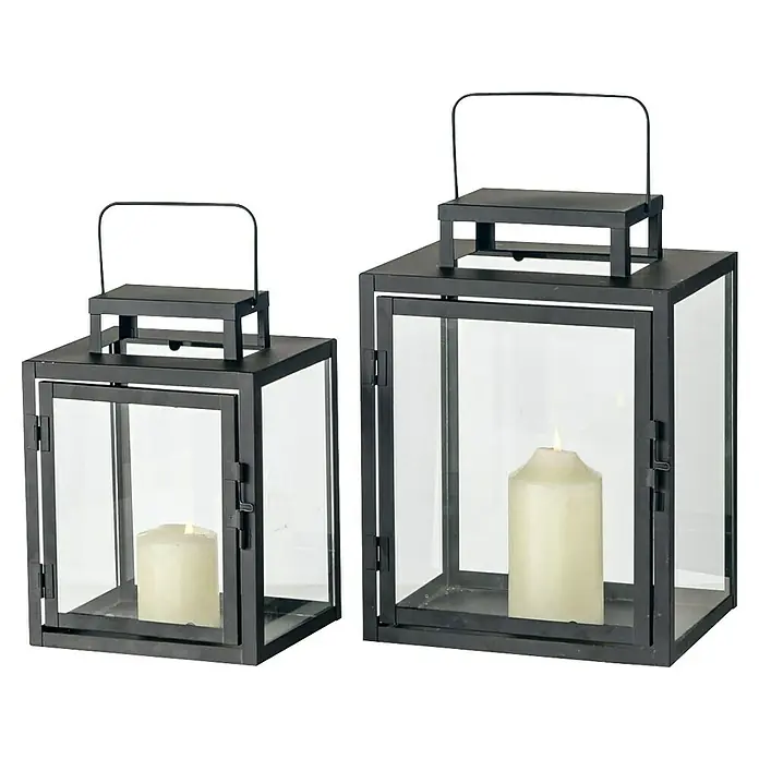 Laterne Damien - L x B x H: 23 x 18 x 31 cm, Schwarz - Zwei schwarze Laternen mit Kerzen darin. Die Laternen sind aus Metall und Glas gefertigt und haben einen Tragegriff.