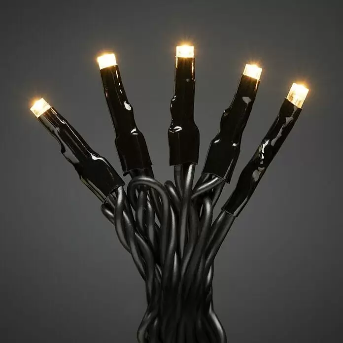 Konstsmide LED-Lichterkette Micro LED - Außen, Lichtfarbe: Bernstein, Anzahl Leuchtmittel: 80 Stk., Netzbetrieben - Nahaufnahme von Lichterkette mit schwarzen Kabeln und fünf leuchtenden warmweißen LED-Birnen.