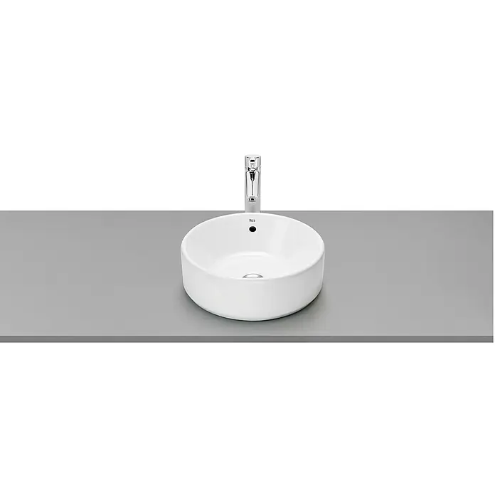 Roca Lavabo Domus - 39 x 39 cm, Con desbordamiento, Blanco - Lavabo sobre encimera blanco con grifo sobre una superficie gris contra un fondo negro.