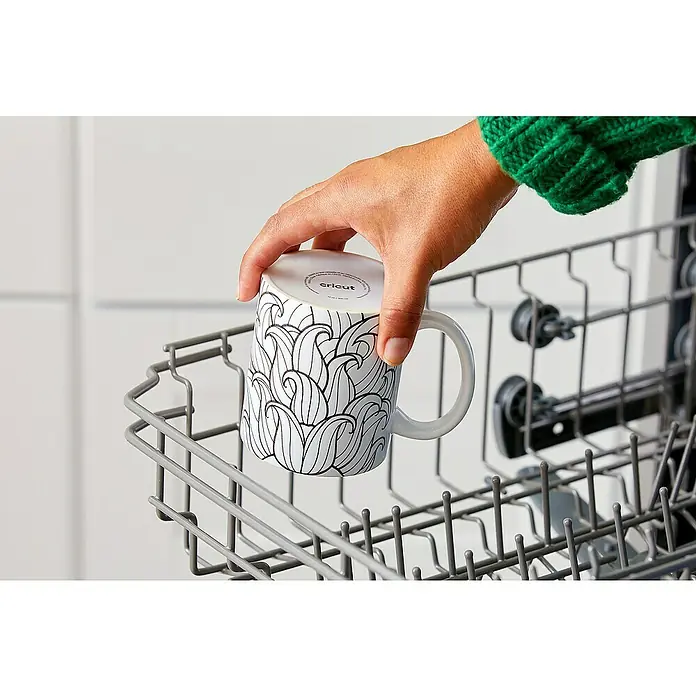 Cricut Transferpresse Mug Press Starter Bundle - Weiß, USB-Kabel - Person stellt eine Cricut Tasse mit Muster in einen Geschirrspüler.