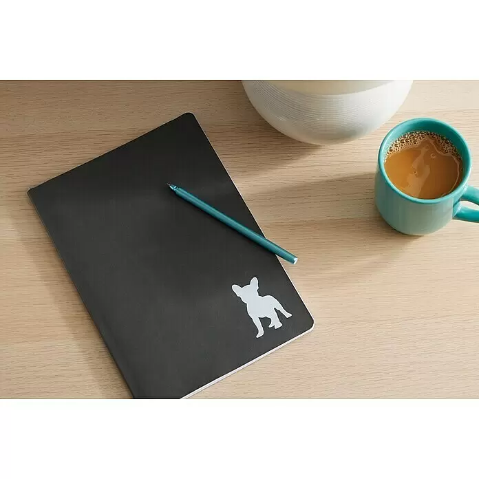 Cricut Joy Schneideplotter Starter Bundle - Türkis/Weiß, Bluetooth, Schnittbreite: 10,4 cm, Schnittlänge: 1,2 m - Dunkelgraues Notizbuch mit weißer Bulldoggen-Silhouette, türkisfarbenem Stift und Kaffeebecher auf hellem Holztisch.