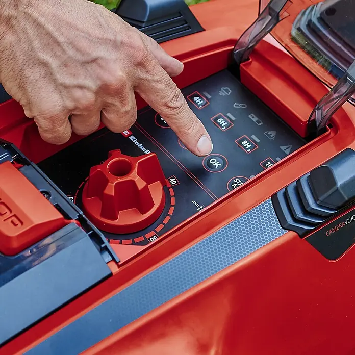 Einhell PXC 18V Mähroboter FREELEXO CAM 500 - 500 m², Schnittbreite: 18 cm, Kamera-gestützte Navigation - Nahaufnahme eines Einhell-Robotermähers, bei dem eine Hand die "OK"-Taste auf der Bedienoberfläche des Geräts drückt.