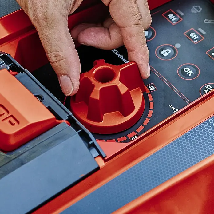 Einhell PXC 18V Mähroboter FREELEXO CAM 500 - 500 m², Schnittbreite: 18 cm, Kamera-gestützte Navigation - Detailaufnahme einer Hand, die einen orangefarbenen Drehknopf an einer Einhell-Maschine einstellt.