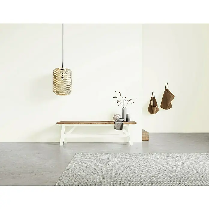 SCHÖNER WOHNEN-Farbe Naturell Wandfarbe Kreidefarbe - Schneegestöber - dezentes Weiß, Matt, 1 l, Konservierungsmittelfrei - Eine moderne Inneneinrichtung mit einer Lampe, einer Holzbank mit Deko und einem grauen Teppich.