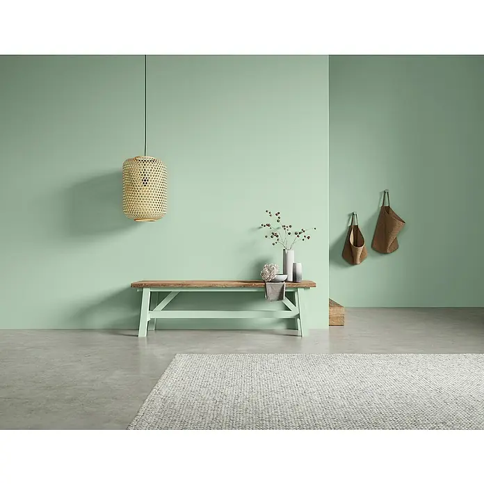 SCHÖNER WOHNEN-Farbe Naturell Wandfarbe Kreidefarbe - Frühlingserwachen - leichtes Olivgrün, Matt, 1 l, Konservierungsmittelfrei - Eine rustikale Holzbank mit mintgrünem Gestell und einer gewebten Hängelampe, die eine gemütliche Atmosphäre in einem stilvollen Raum erzeugt.