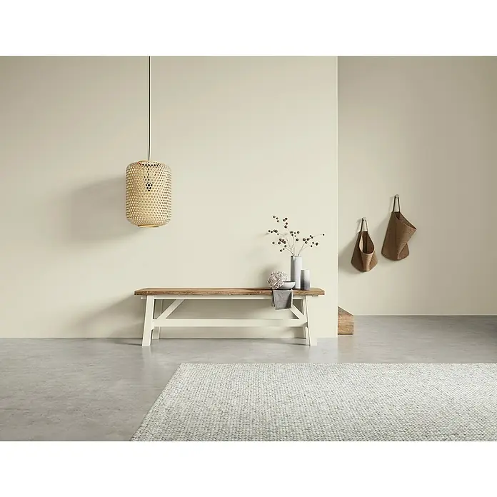 SCHÖNER WOHNEN-Farbe Naturell Wandfarbe Kreidefarbe - Windstille - feines Hellgrau, Matt, 2,5 l, Konservierungsmittelfrei - Innenaufnahme eines skandinavisch inspirierten Raumes mit einer Holzbank und einer geflochtenen Lampe, die ein minimalistisches Ambiente erzeugt.