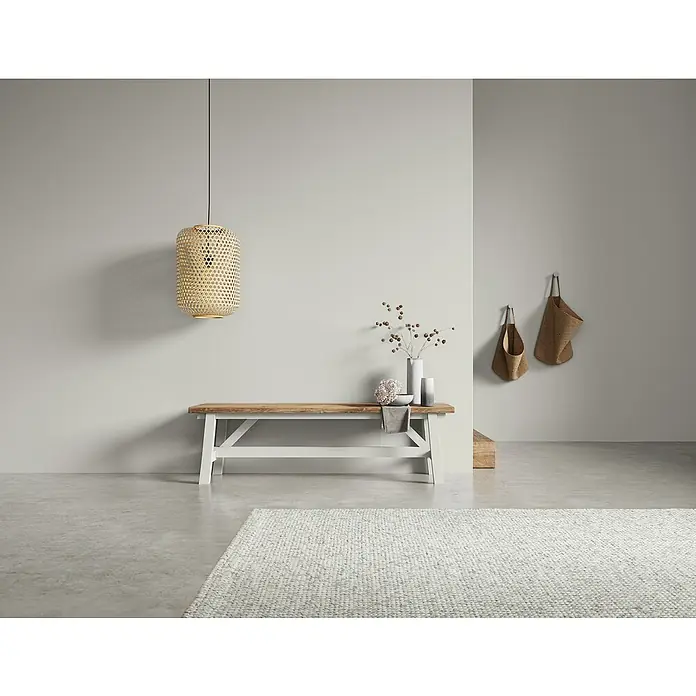 SCHÖNER WOHNEN-Farbe Naturell Wandfarbe Kreidefarbe - Wolkenspiel - kühles Grau, Matt, 2,5 l, Konservierungsmittelfrei - Einrichtungsfoto mit einer dekorativen Bank mit Holztischplatte und weiß lackiertem Fußgestell, ergänzt durch eine hängende Rattanlampe.