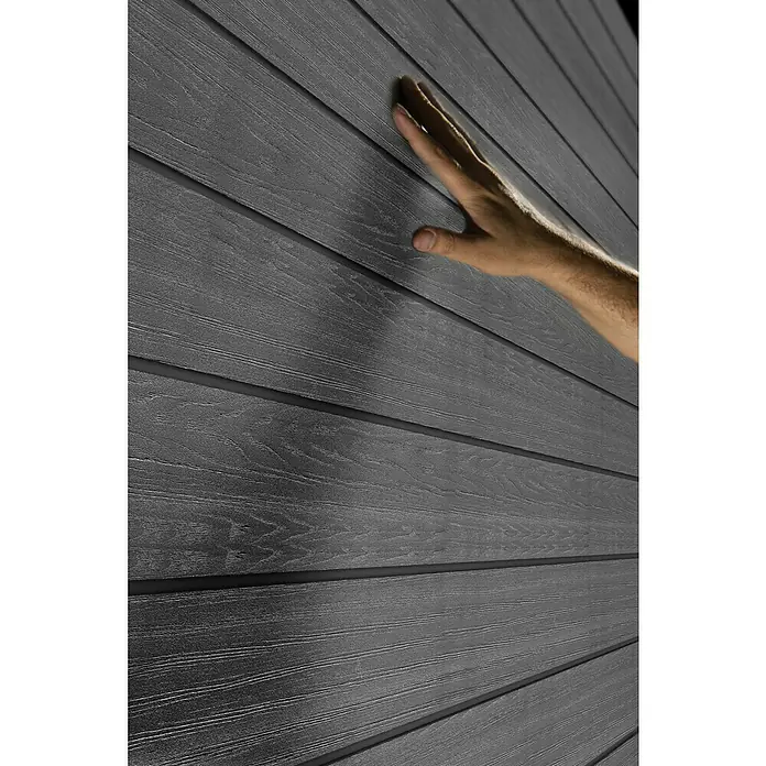 Keter Gerätehaus Newton 7511 - Außenmaß inkl. Dachüberstand (B x T): 228 x 350 cm, Kunststoff, Schiefergrau, 7,98 m² - Nahaufnahme einer grauen Holzverkleidung mit einer Hand, die die Textur des Produkts zeigt.