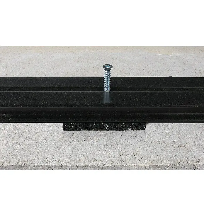 Kovalex Betonschraube WPC-Unterkonstruktion - Durchmesser: 7,5 mm, Länge: 52 mm, 50 Stk. - Nahaufnahme einer schwarzen Fußleiste, die mit einer Schraube an einer Betonwand befestigt ist, mit einem Gummistreifen zur zusätzlichen Abdichtung.