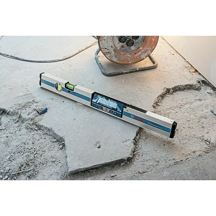 Bosch Professional Digitale Wasserwaage GIM 60 L - Länge: 61,8 cm - Eine digitale Wasserwaage von Bosch Professional, die auf einem unebenen Betonboden liegt, ideal für präzise Messungen auf der Baustelle.