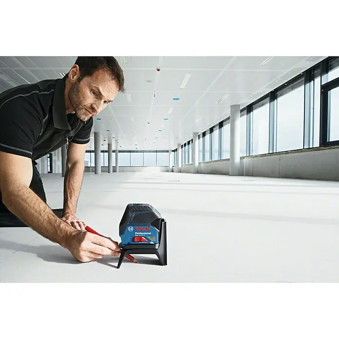 Bosch Professional Kombilaser GCL 2-15 - Arbeitsbereich: Ca. 15 m, 6 -tlg. - Ein Mann bedient einen Bosch Professional GCL 2-15 G Linienlaser in einem hellen, modernen Raum. Das Werkzeug wird zur präzisen Ausrichtung genutzt.