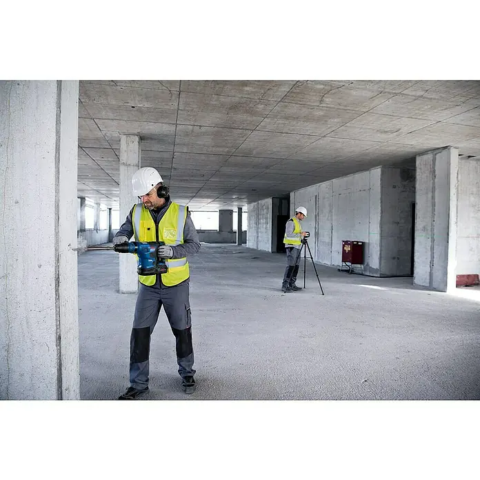 Bosch Professional Kombilaser GCL 2-50 G - Max. Arbeitsbereich: 50 m, 5 -tlg. - Ein Bauarbeiter bohrt mit einem Bosch Bohrhammer in eine Säule, während ein Kollege im Hintergrund Vermessungsarbeiten durchführt.