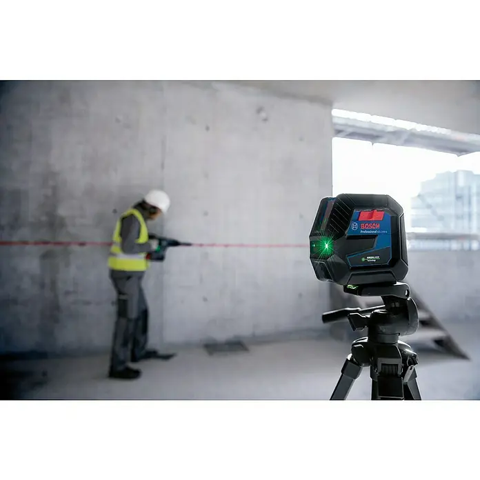 Bosch Professional Kombilaser GCL 2-50 G - Max. Arbeitsbereich: 50 m, 5 -tlg. - Ein Bosch Professional Laser-Entfernungsmesser auf einem Stativ mit einem Arbeiter im Hintergrund, der in eine Wand bohrt.