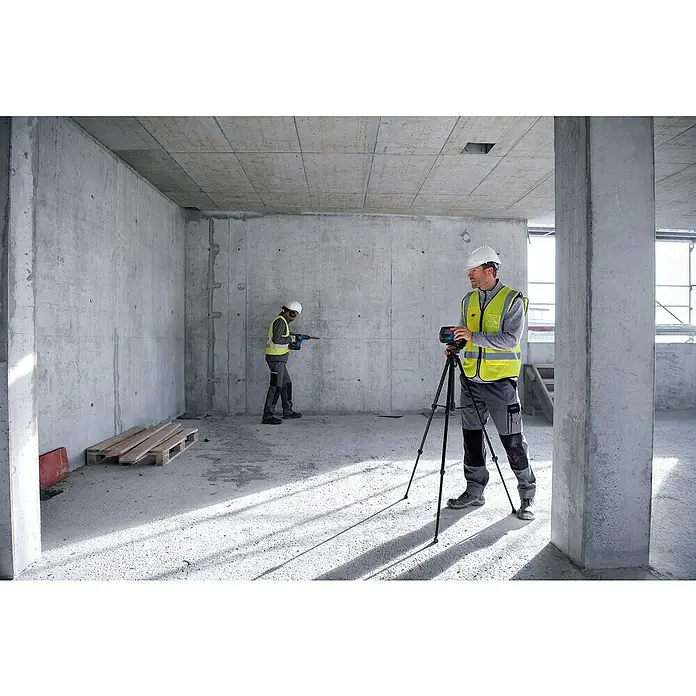 Bosch Professional Kombilaser GCL 2-50 G - Max. Arbeitsbereich: 50 m, 5 -tlg. - Baustellenaufnahme mit einem Bosch Professional Linienlaser auf einem Stativ, während ein Arbeiter bohrt.