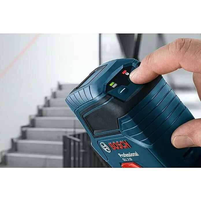 Bosch Professional Linienlaser GLL 2-10 - Max. Arbeitsbereich: 10 m, 3 -tlg. - Blau-schwarzes Bosch-Laser-Nivelliergerät, von einer Hand gehalten, projiziert eine rote Linie an eine Wand nahe einer Treppe.