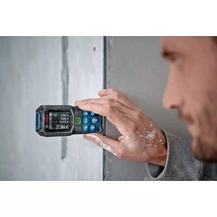Bosch Professional Laserentfernungsmesser GLM 50-27 CG - Anzahl Akkus: 1 Akku, Messbereich: 0,05 - 50 m - Schwarz-blaues Bosch Laser-Messgerät wird von einer Person an eine Wand gehalten und zeigt Längenmaße wie 26,344m an.
