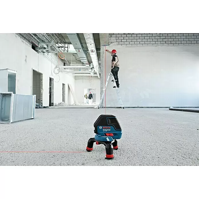 Bosch Professional Linienlaser GLL 3-50 - Arbeitsbereich: 50 m (mit Empfänger), 6 -tlg. - Ein blau-schwarzer Bosch Professional GLL 3-80 Laser-Nivellierer projiziert rote Linien auf einer Baustelle, wo ein Arbeiter misst.