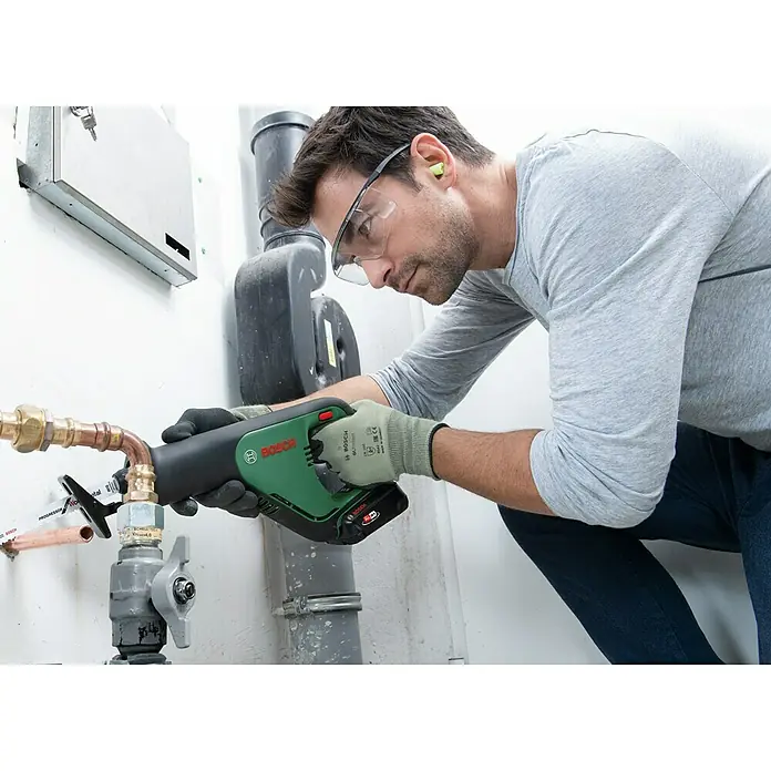 Bosch Power for All 18V Akku-Säbelsäge AdvancedRecip 18 - 18 V, 1 Akku, 2 Ah, Leerlaufhubzahl: 0 /min - 3.100 /min - Ein Installateur benutzt eine Bosch Akku-Rohrsäge, um ein Kupferrohr zu durchtrennen. Sicherheitsausrüstung wird getragen.