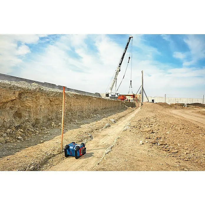 Bosch Professional Rotationslaser GRL 600 CHV - 19 -tlg. - Das Bild zeigt einen Bosch Rotationslaser GRL 300 HV Professional mit Nivellierlatte auf einer Baustelle vor einer Baugrube.