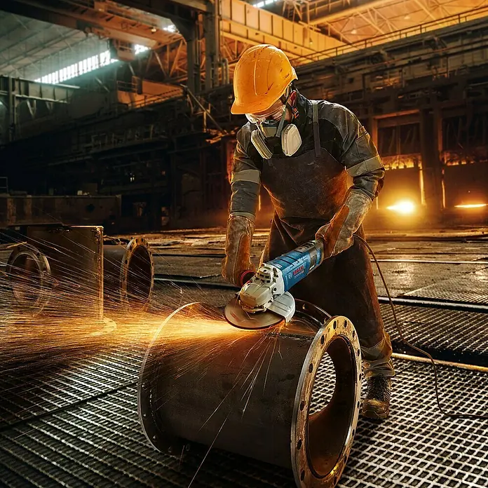 Bosch Professional Elektro-Winkelschleifer GWS 17-150 S - 1.700 W, Durchmesser Scheibe: 150 mm, Leerlaufdrehzahl: 2.400 U/min - 9.700 U/min - Arbeiter mit Winkelschleifer von Bosch in einer Fabrik beim Funken sprühen.