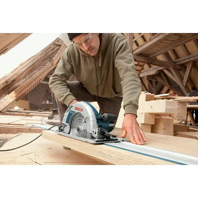 Bosch Professional Handkreissäge GKS 85 G - 2.200 W, Durchmesser Sägeblatt: 235 mm - Ein Mann benutzt eine Bosch Kreissäge, um Holz zu schneiden. Sicherheit steht an erster Stelle, wie die Schutzbrille zeigt.