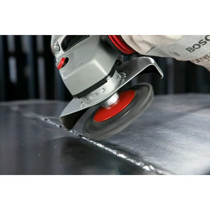 Bosch Professional Elektro-Winkelschleifer GWS 14-125 S - 1.400 W, Durchmesser Scheibe: 125 mm, Leerlaufdrehzahl: 2.800 U/min - 11.500 U/min - Winkelschleifer mit rotierender Drahtbürste zum Entgraten einer Metalloberfläche. Das Werkzeug stammt von Bosch und wird von einer Person mit Handschuhen bedient.