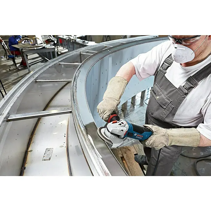 Bosch Professional Elektro-Winkelschleifer GWS 17-125 - 1.700 W, Durchmesser Scheibe: 125 mm, Leerlaufdrehzahl: 11.500 U/min - Ein Arbeiter glättet eine Metalloberfläche mit einem blauen Bosch Winkelschleifer. Schutzkleidung wird getragen für die Arbeitssicherheit.
