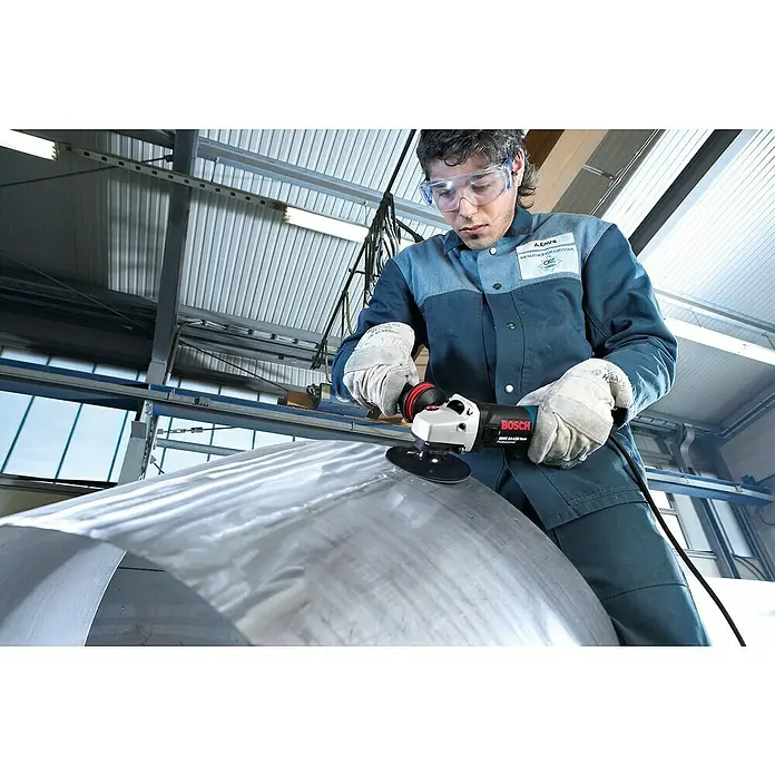 Bosch Professional Elektro-Winkelschleifer GWS 17-150 S - 1.700 W, Durchmesser Scheibe: 150 mm, Leerlaufdrehzahl: 2.400 U/min - 9.700 U/min - Ein Arbeiter benutzt eine Bosch GWS 14-125 S Winkelschleifer zum Schleifen eines Metallstücks. Schutzbrille und Handschuhe sind dabei unerlässlich.