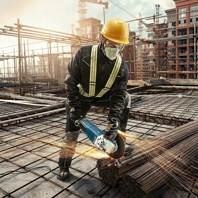 Bosch Professional Elektro-Winkelschleifer GWS 17-150 S - 1.700 W, Durchmesser Scheibe: 150 mm, Leerlaufdrehzahl: 2.400 U/min - 9.700 U/min - Ein Bauarbeiter benutzt einen Bosch Winkelschleifer zum Schneiden von Metall auf einer Baustelle, Funken sprühen.