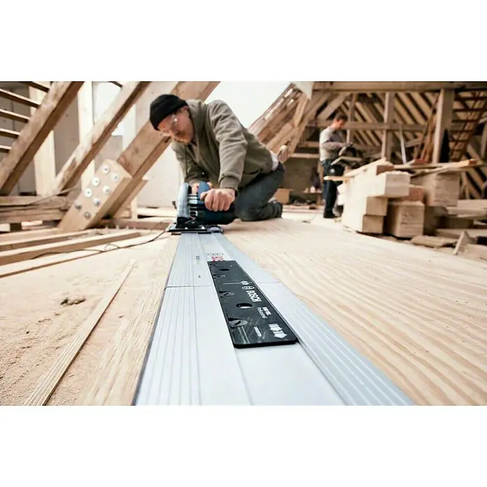 Bosch Professional Handkreissäge GKS 85 G - 2.200 W, Durchmesser Sägeblatt: 235 mm - Ein Handwerker benutzt eine Bosch-Tauchsäge mit Führungsschiene, um präzise Holzschnitte durchzuführen, während im Hintergrund ein weiterer Arbeiter steht.