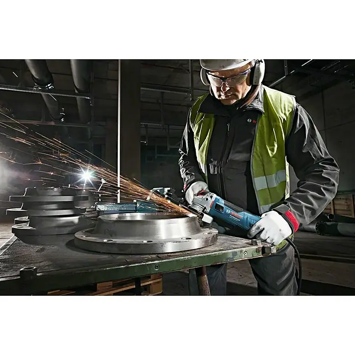 Bosch Professional Elektro-Winkelschleifer GWS 17-125 S - 1.700 W, Durchmesser Scheibe: 125 mm, Leerlaufdrehzahl: 2.800 U/min - 11.500 U/min - Ein Mann schleift Metall mit einem blauen Bosch Winkelschleifer, Funken sprühen, während er an einem runden Werkstück arbeitet, geschützt durch Sicherheitsausrüstung.