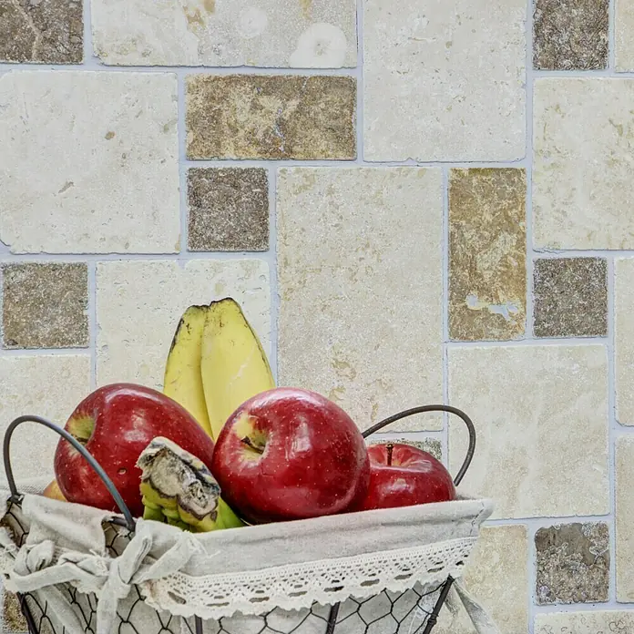 Mosaikfliese Mix Travertine XNT 40602 - 30,5 x 30,5 cm, Beige, Matt - Nahaufnahme von roten Äpfeln und Bananen in einem Drahtkorb mit Stoffeinlage, der auf einem Tisch vor einer gemusterten Wand steht.