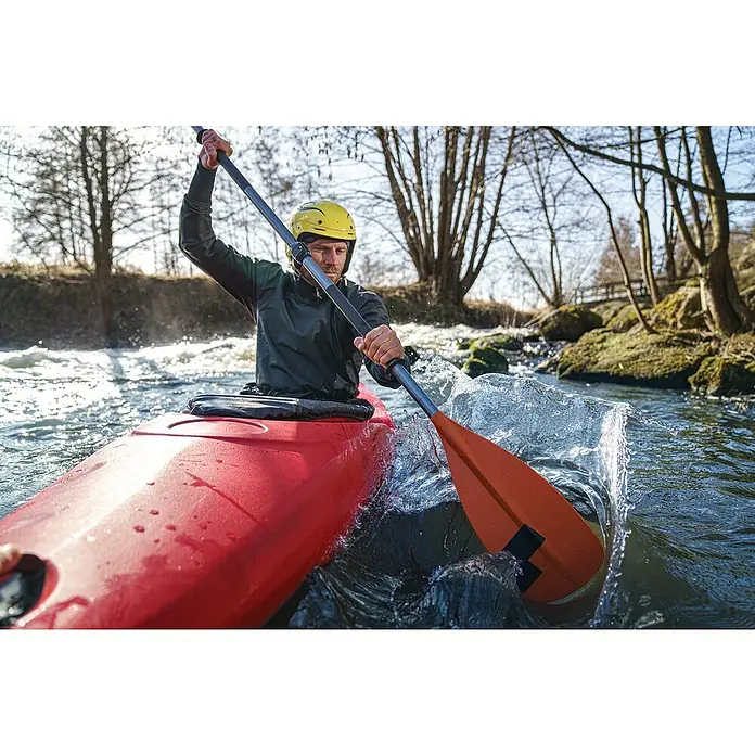 Tesa Ultra Power Unterwasser-Klebeband Under Water - Schwarz, 1,5 m x 50 mm - Ein Kajakfahrer mit gelbem Helm paddelt auf einem Fluss. Das orangefarbene Paddel erzeugt Spritzer im klaren Wasser.