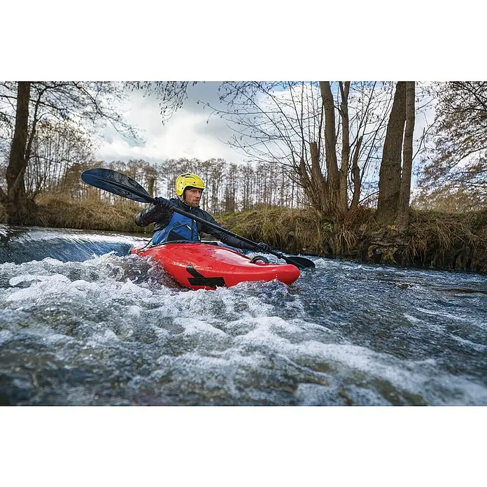 Tesa Ultra Power Unterwasser-Klebeband Under Water - Schwarz, 1,5 m x 50 mm - Ein rotes Kajak gleitet auf einem Fluss mit einem gelben Helm, der von einem Paddler getragen wird, umgeben von Bäumen.