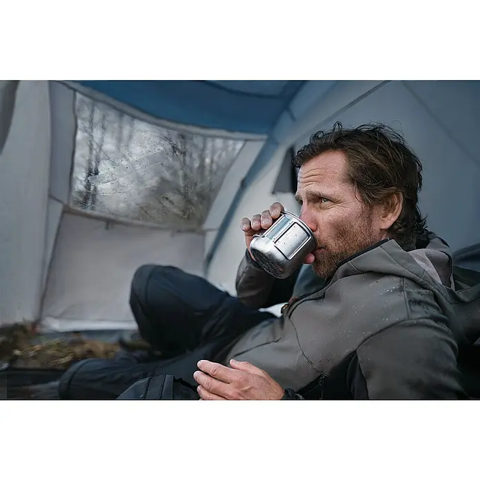 Tesa Ultra Power Reparaturklebeband Clear - Transparent, 10 m x 50 mm - Mann im Zelt trinkt aus einem Metallbecher. Der Becher ist ein robustes Outdoor-Produkt für Campingausflüge.