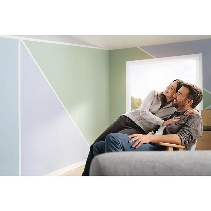Tesa Malerband Perfect+ - 50 m x 19 mm - Ein Paar genießt die Wandgestaltung mit geometrischen Farbakzenten in einem modernen Raum, der durch die kreative Wandgestaltung eine besondere Note erhält.