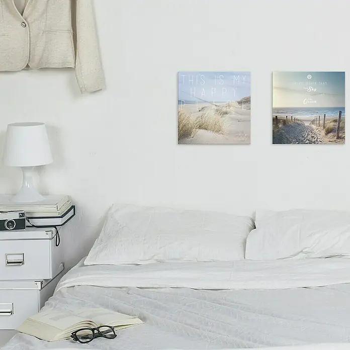ProArt Maritime Glasbild - Dream, B x H: 50 x 50 cm - Schlafzimmerdekor mit zwei quadratischen Leinwandbildern, die Strandszenen zeigen, und einer weißen Bettwäsche-Garnitur.