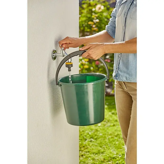 Neptun Hahnverbinder - 33,3 mm (1″), 26,5 mm (¾″), 21 mm (½″) - Eine Person füllt einen grünen Eimer mit Wasser aus einem Wasserhahn im Freien, um Gartenarbeiten zu erledigen.