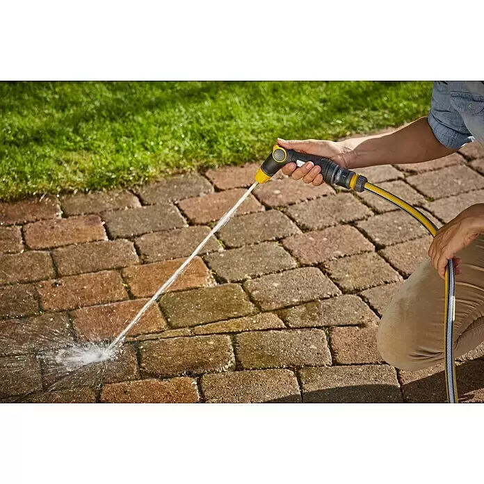 Neptun Brause - Kunststoff - Person sprüht mit schwarzer und gelber Gartenspritze Wasser auf einen gepflasterten Weg.