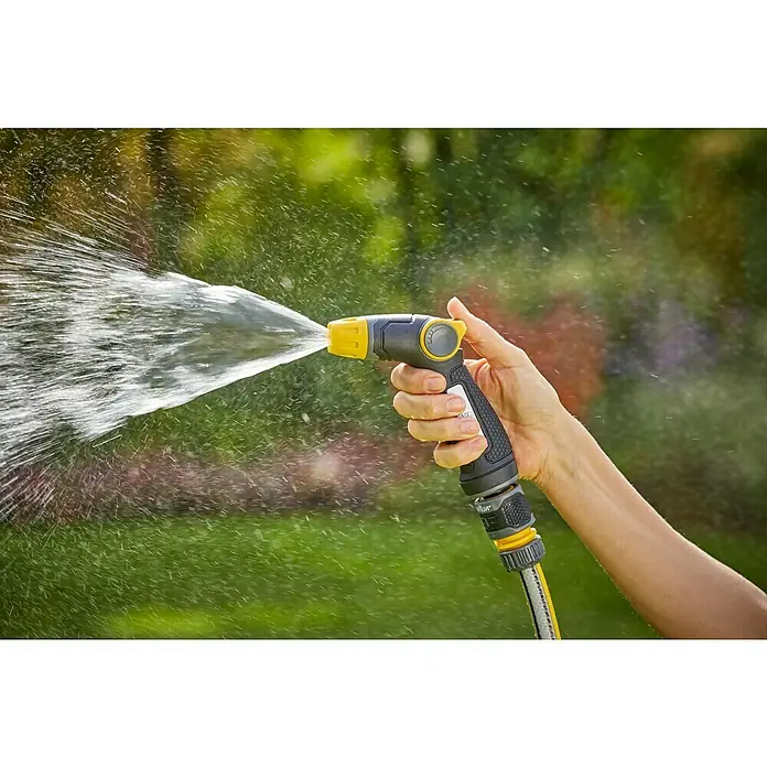 Neptun Brause - Kunststoff - Eine Person hält eine gelb-schwarze Gartenspritze, die Wasser verspritzt, vor einem grünen, verschwommenen Hintergrund.