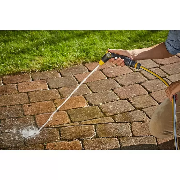 Neptun Brause - Kunststoff - Person hält eine schwarz-gelbe Gartenspritze und besprüht eine Ziegelterrasse neben einem Rasen mit Wasser.