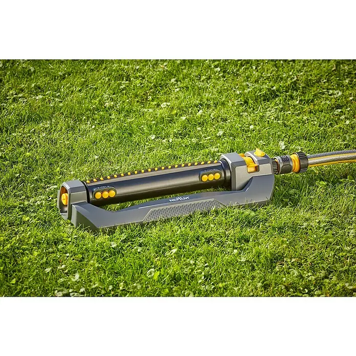Neptun Viereckregner - Max. Regnerfläche: 460 m² - Ein Rasensprenger von NEPTUN liegt auf einem grünen Rasen. Der Sprenger ist schwarz und grau mit gelben Akzenten und einem gelben Schlauch.